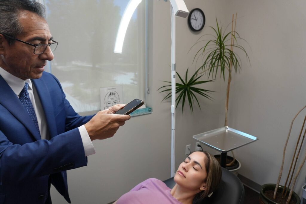 Dr. Mark Paz reviewing a patient’s face during a consultation at NuVida Medical and Aesthetics