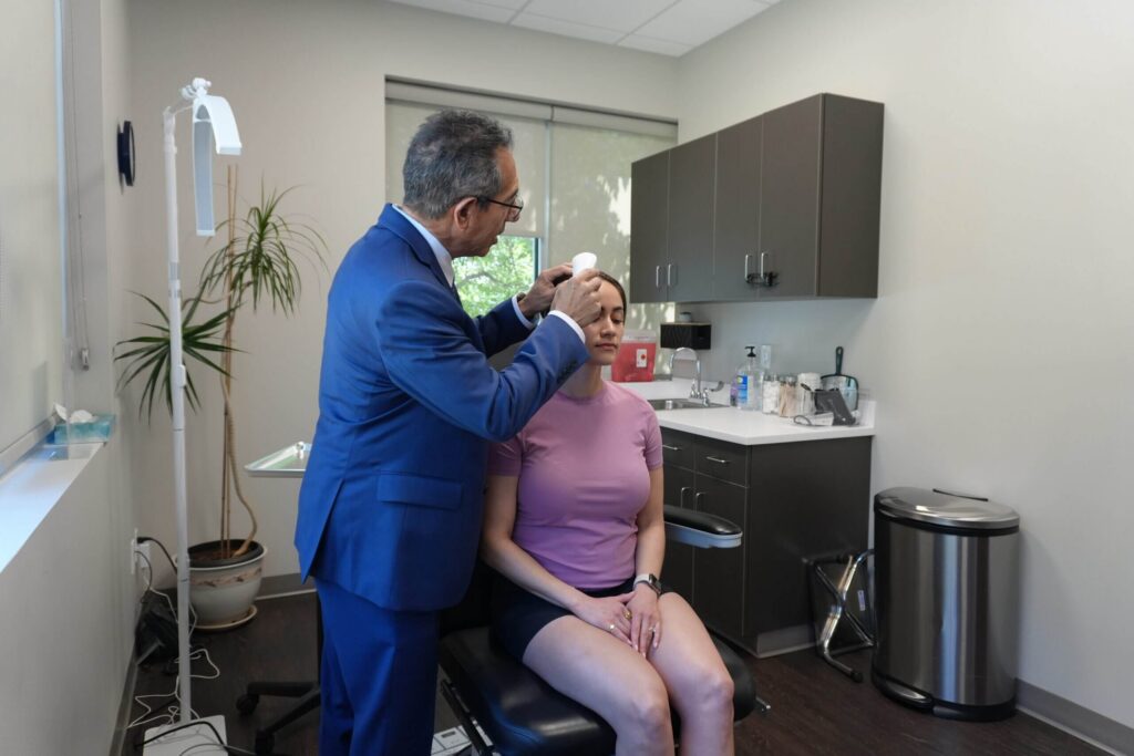 Dr. Mark Paz examining a patient’s skin during a consultation at NuVida Medical and Aesthetics