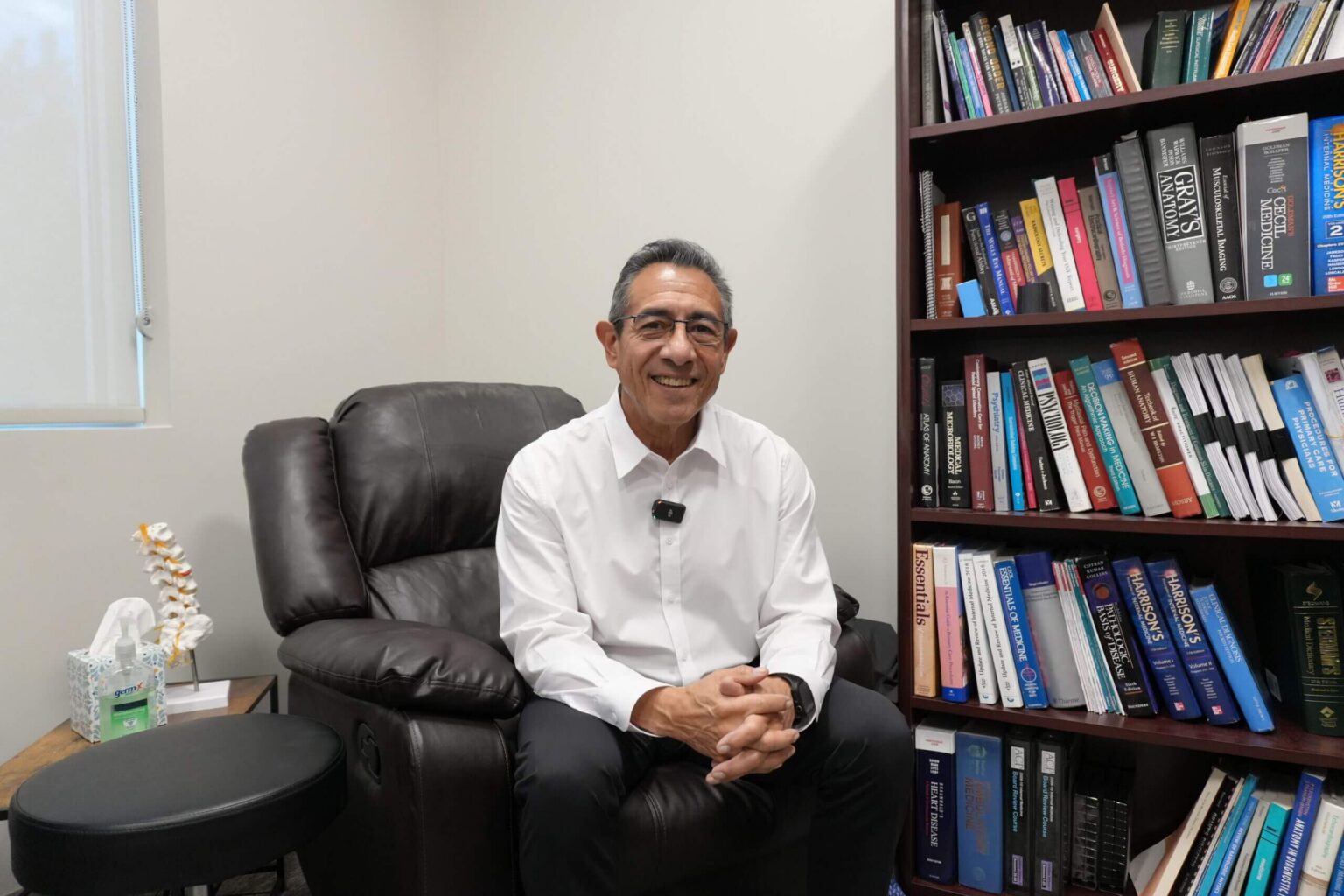 Dr. Mark Paz seated in front of a bookshelf at NuVida Medical and Aesthetics